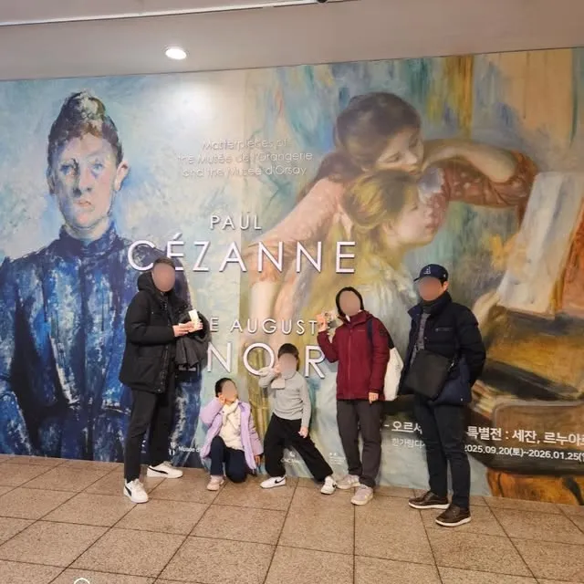 세잔과 르누아르 전시 포스터 앞에 선 가족들.